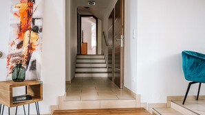 A modern hallway with a wooden bench, a teal chair, and a staircase leading to another room. - dasWeinbergblick - Landhaus dasThomas by Interhome (Henndorf im Burgenland)