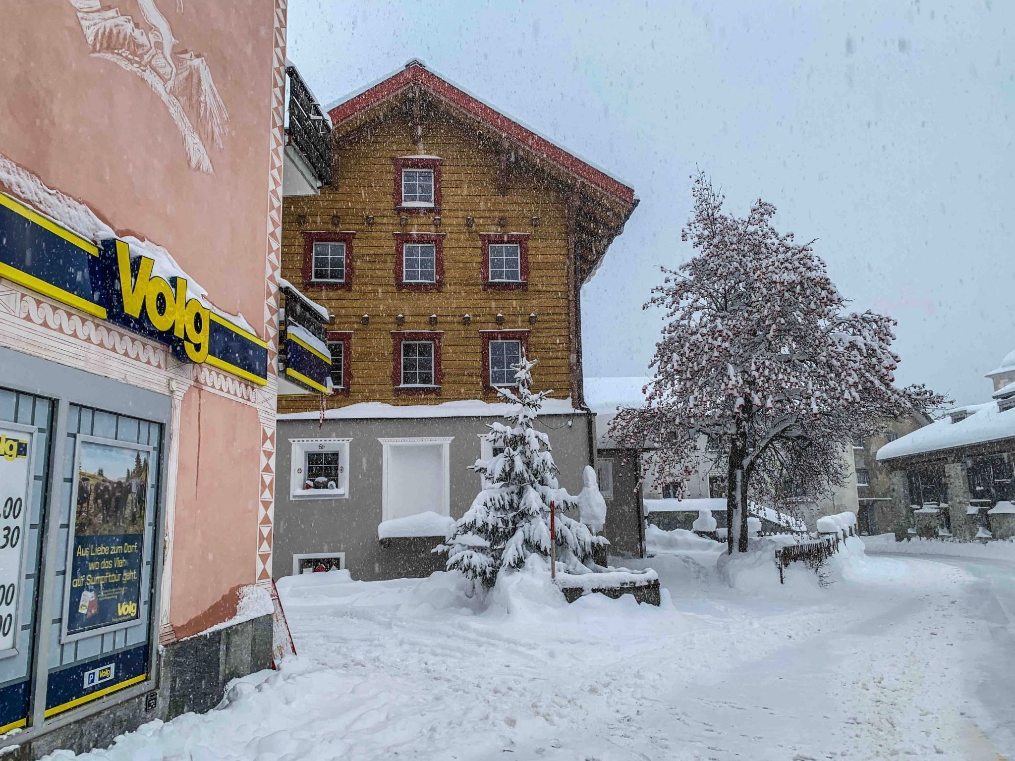 Een met sneeuw bedekte straat met een gebouw, voorzien van een geel bord waarop de tekst 