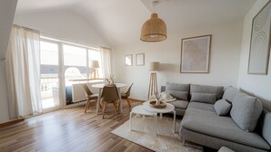Una sala moderna con un sofá gris, una mesa de centro redonda y un comedor con mesa y sillas.