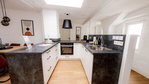 Une cuisine moderne dotée d’un îlot central, de meubles blancs et d’un plan de travail noir.