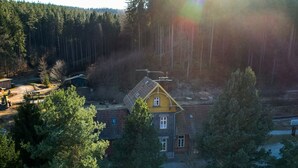 Una casa con tetto spiovente, circondata da una fitta foresta.