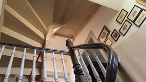 Una scala con balaustre bianche e corrimano scuro, che conduce a un piano superiore.