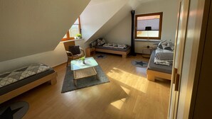 Ett rum i loftstil med ett sluttande tak, en säng, en soffa, ett litet bord och ett fönster med utsikt.
