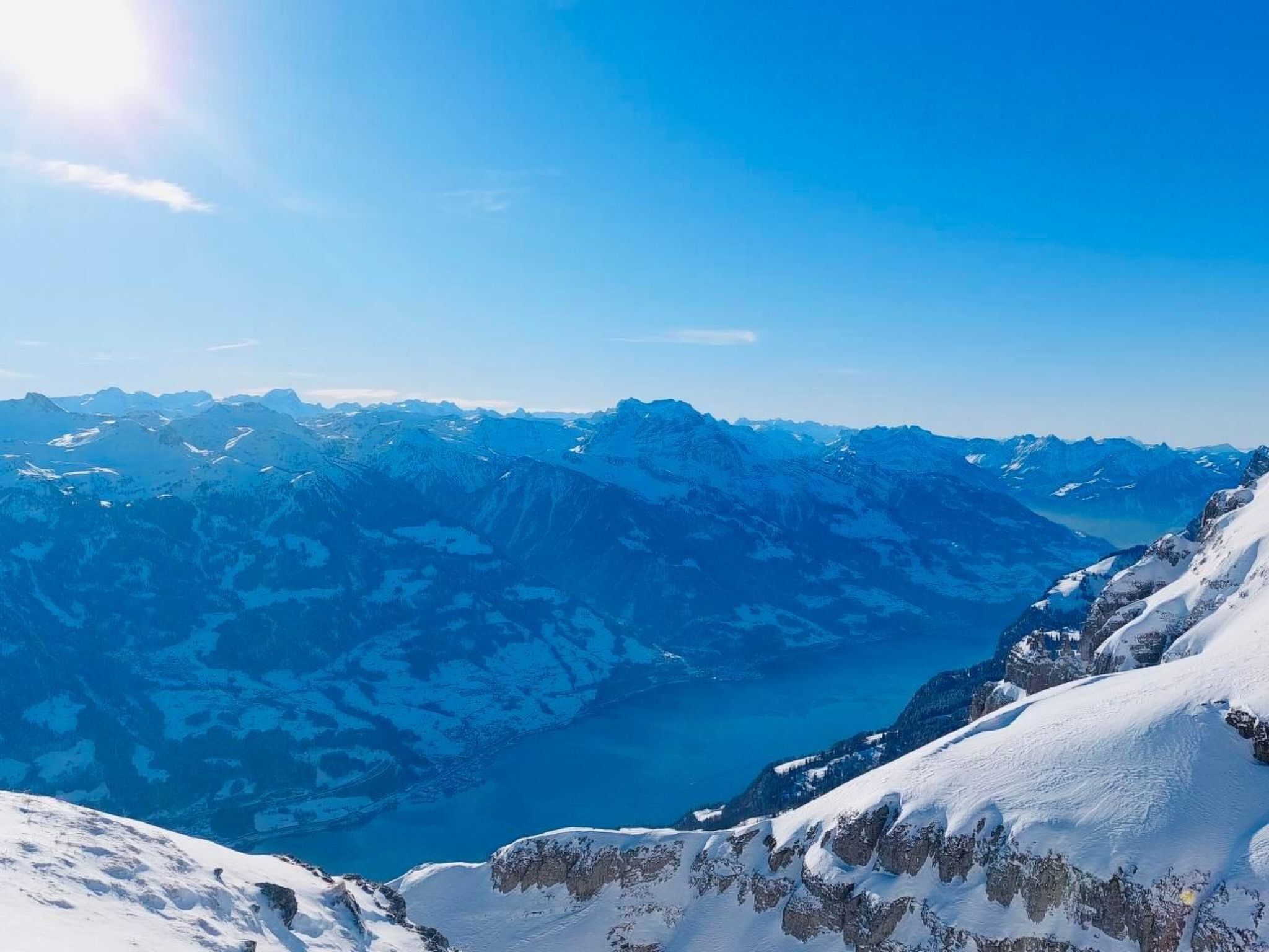 Vista panorámica de un paisaje montañoso con picos nevados y un cielo azul despejado.