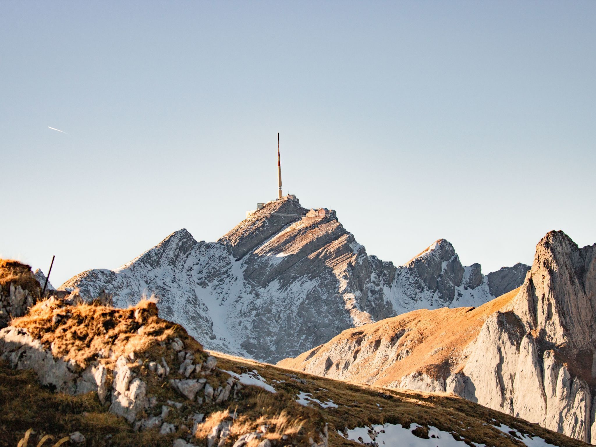 Paisaje montañoso con un pico destacado y una estructura alta en la cima, probablemente un monumento o torre.