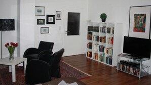 Ein Wohnzimmer mit Bücherregal, Fernseher und Tür.