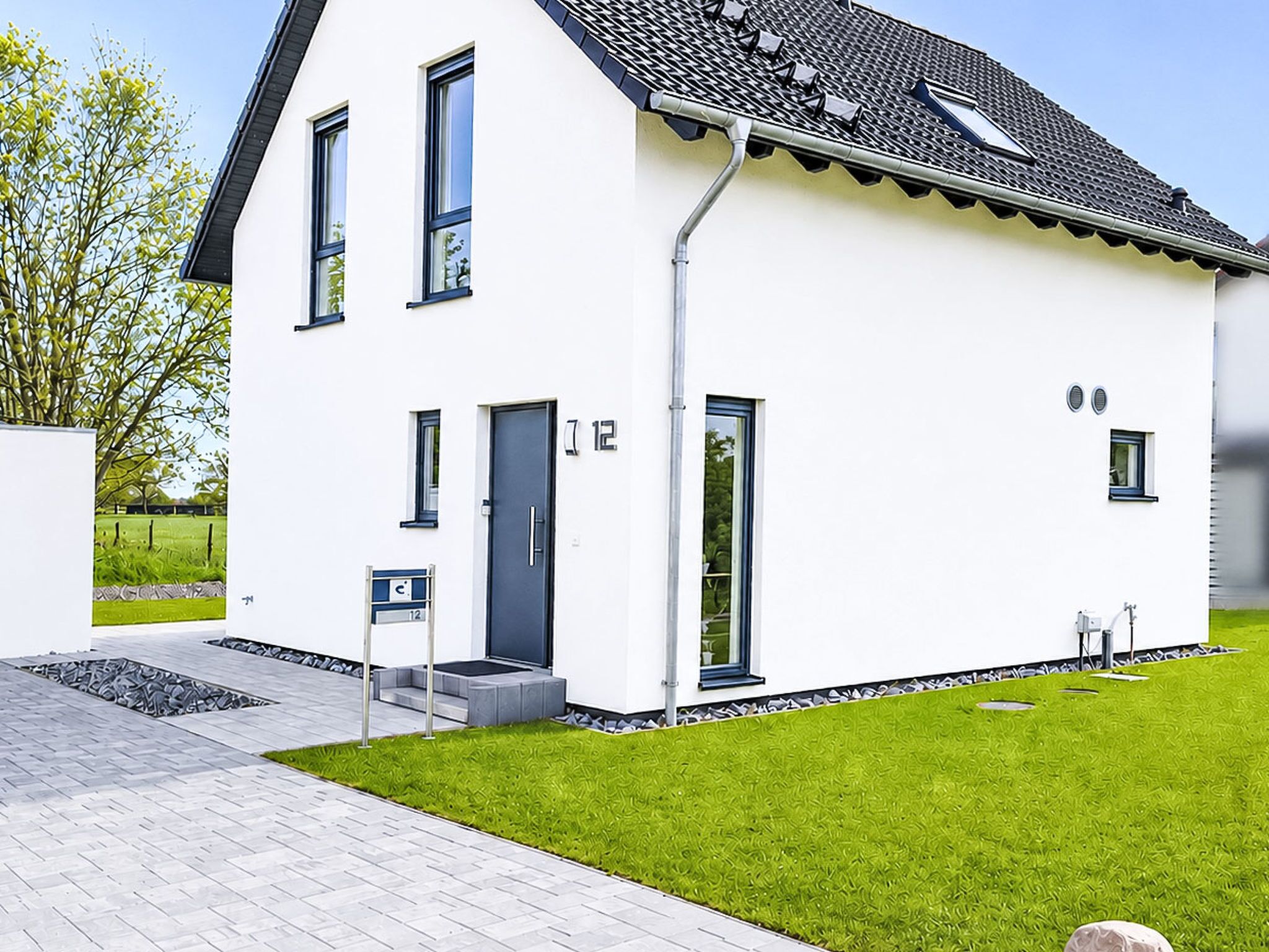 A modern two-story house with a flat roof, large windows, and a well-maintained lawn.
