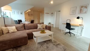 A modern living room with a brown sofa, a white coffee table, and a desk with a chair. There are framed pictures on the walls and a rug on the floor. - am Ruhrtalradweg Arnsberg by Interhome (Arnsberg)