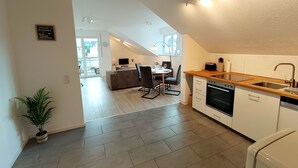 A modern kitchen with a wooden countertop, built-in oven, and white cabinetry. There is a dining area with a table and chairs, and a potted plant in the corner. - am Ruhrtalradweg Arnsberg by Interhome (Arnsberg)