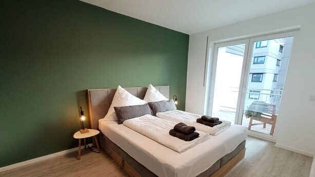 A bedroom with a large bed, a nightstand, and a view of a building through a glass door. - am Ruhrtalradweg Arnsberg by Interhome (Arnsberg)