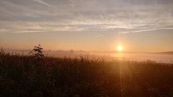 Un lever de soleil sur un champ, avec un horizon lointain.