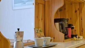 Una cucina con mobili in legno, un piano di lavoro in marmo, una macchina da caffè e una tazza di caffè.