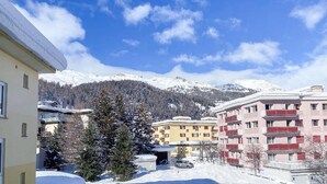 Paesaggio innevato con edifici e montagne sullo sfondo.