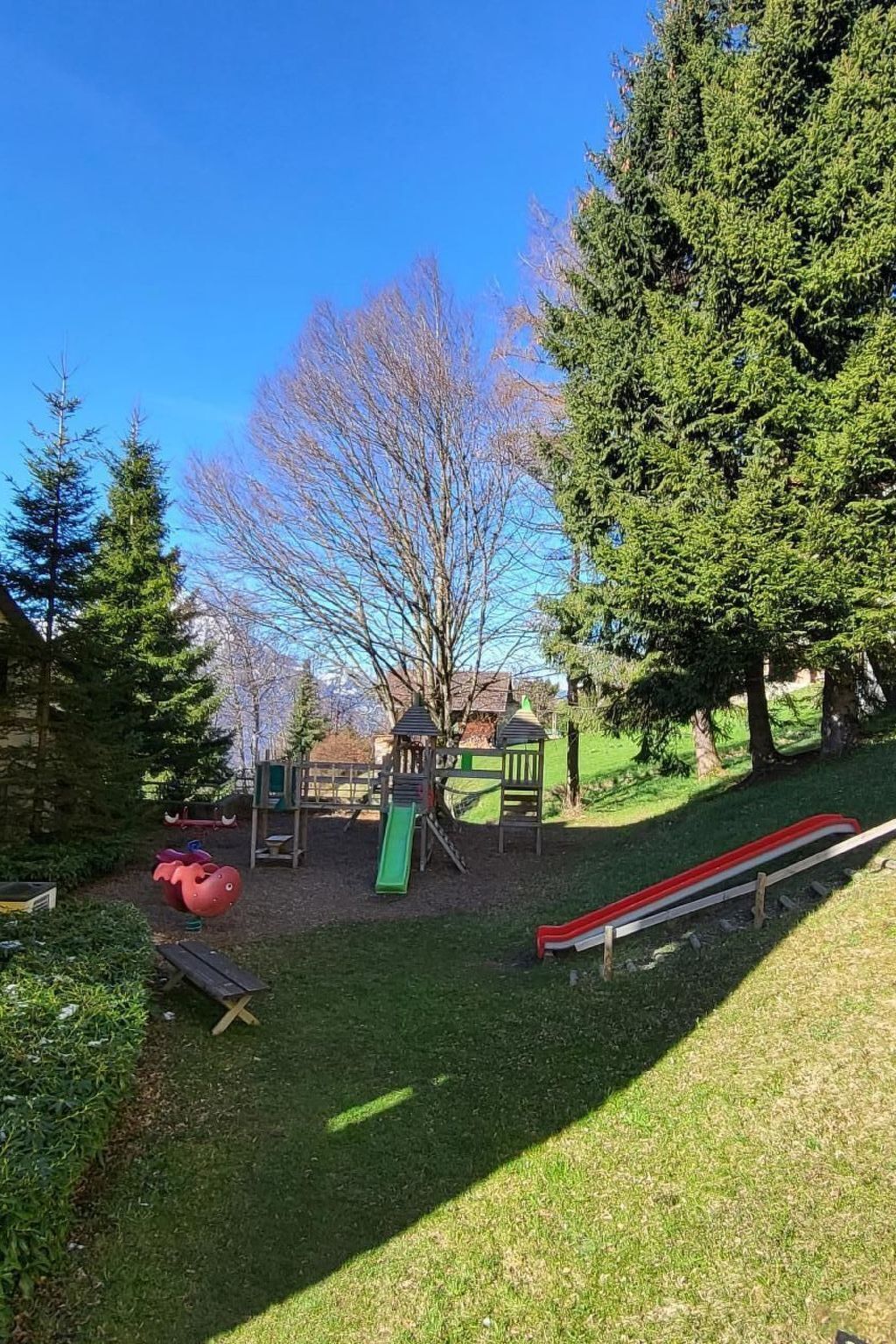 A playground with a slide, climbing structures, and a red and white slide.