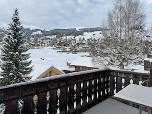 Een besneeuwd bergdorp met houten huizen en een balkon met een leuning.