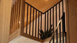 A loft-style bedroom with a wooden staircase, a bed with pillows, and a window with curtains. - Casa Ladina 4 by Interhome (Falera)