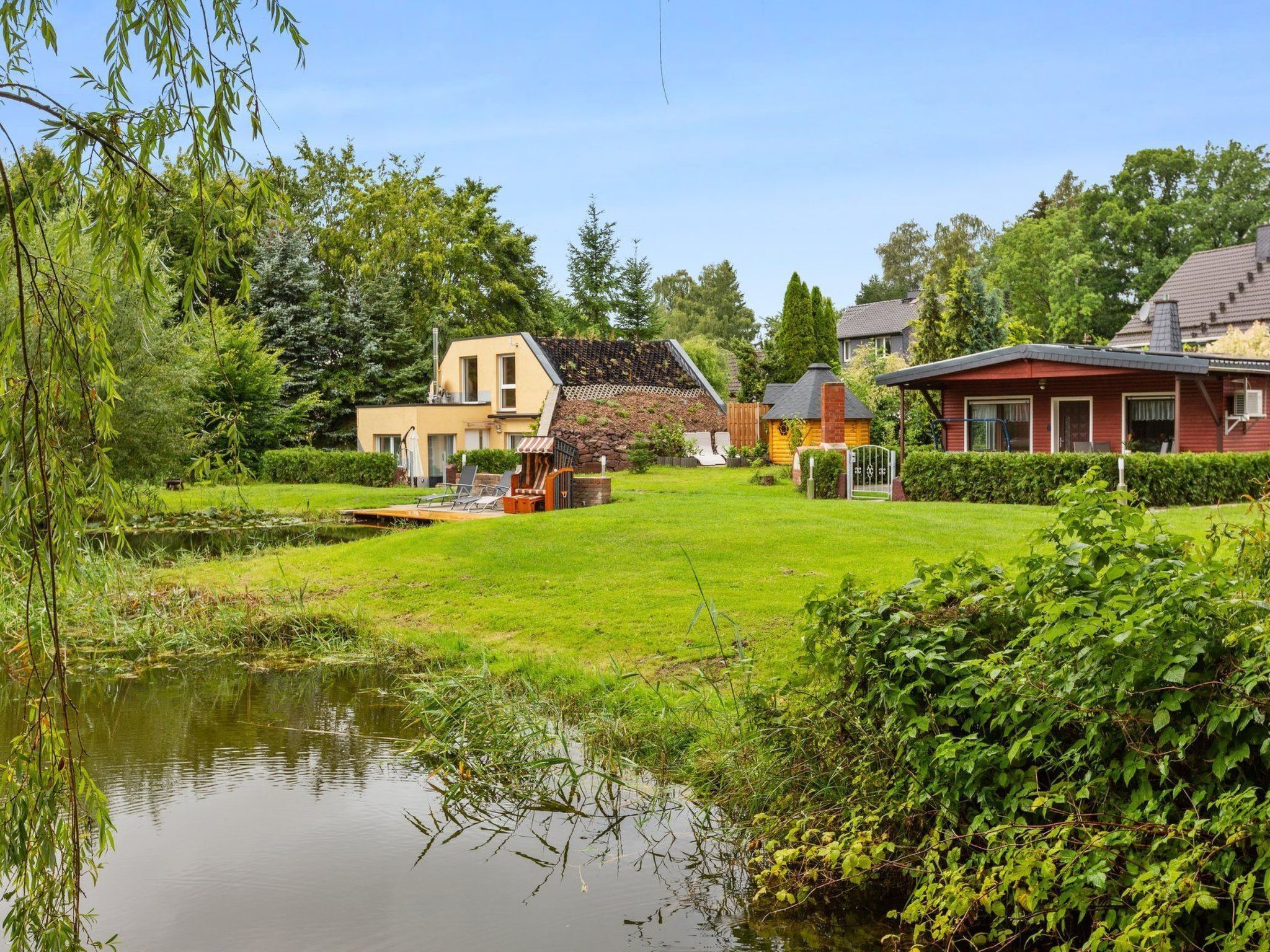 Ein Wohngebiet mit Teich, Holzterrasse und Häusern mit unterschiedlicher Architektur.