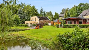 Ein Wohngebiet mit Teich, Holzterrasse und Häusern mit unterschiedlicher Architektur.
