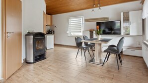 Eine moderne Küche mit Einbauherd, einem Essbereich mit Tisch und Stühlen sowie einem an der Wand befestigten Fernseher.