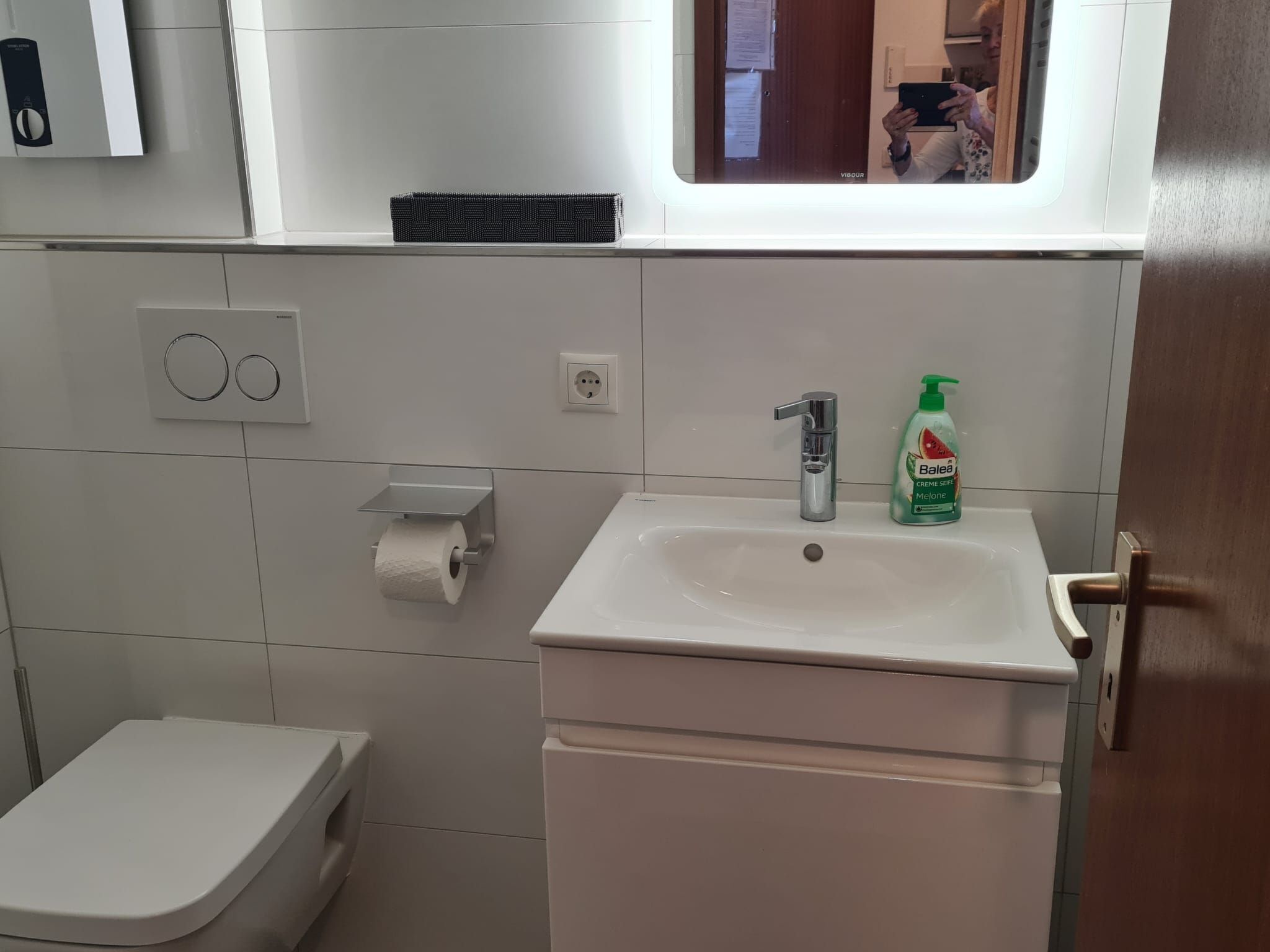 Une salle de bain avec des toilettes, un lavabo et un miroir.