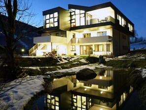 A modern two-story house with large windows, a balcony, and a pond in the foreground. - Top Level Apartments by Interhome (Aschau im Zillertal)