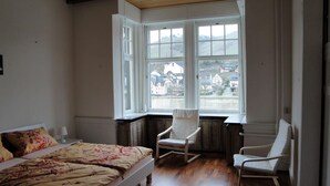 Ett sovrum med en säng, en stol och utsikt över ett bostadsområde genom ett fönster.