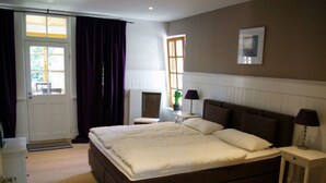 A bedroom with a large bed, bedside tables, a radiator, a window, and a door. - Seerose by Interhome (Bleckede)