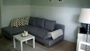 A living room with a grey sofa, white cushions, a small white table with candles, and a white lamp. - Seerose by Interhome (Bleckede)