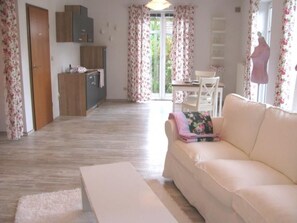 Sala de estar com sofá, mesa de centro e área de jantar com mesa e cadeiras.