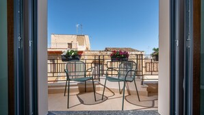 A balcony with two chairs and a table, overlooking a building with a tiled roof and potted plants. - Guesthouse in the historic center - Bed 10.5 Design Suite (Castellammare del Golfo)
