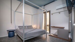 A modern bedroom with a four-poster bed, a small round table, and a built-in bench. - Guesthouse in the historic center - Bed 10.5 Design Suite (Castellammare del Golfo)