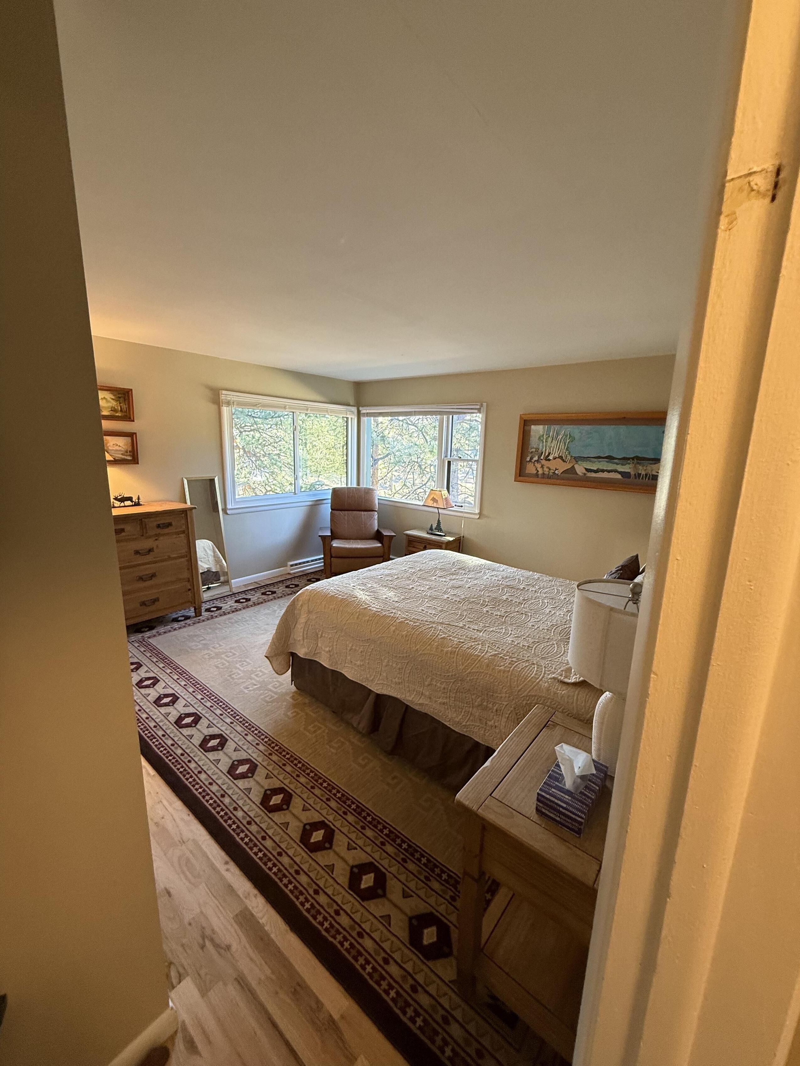 A bedroom with a bed, a chair, a desk, and a window.