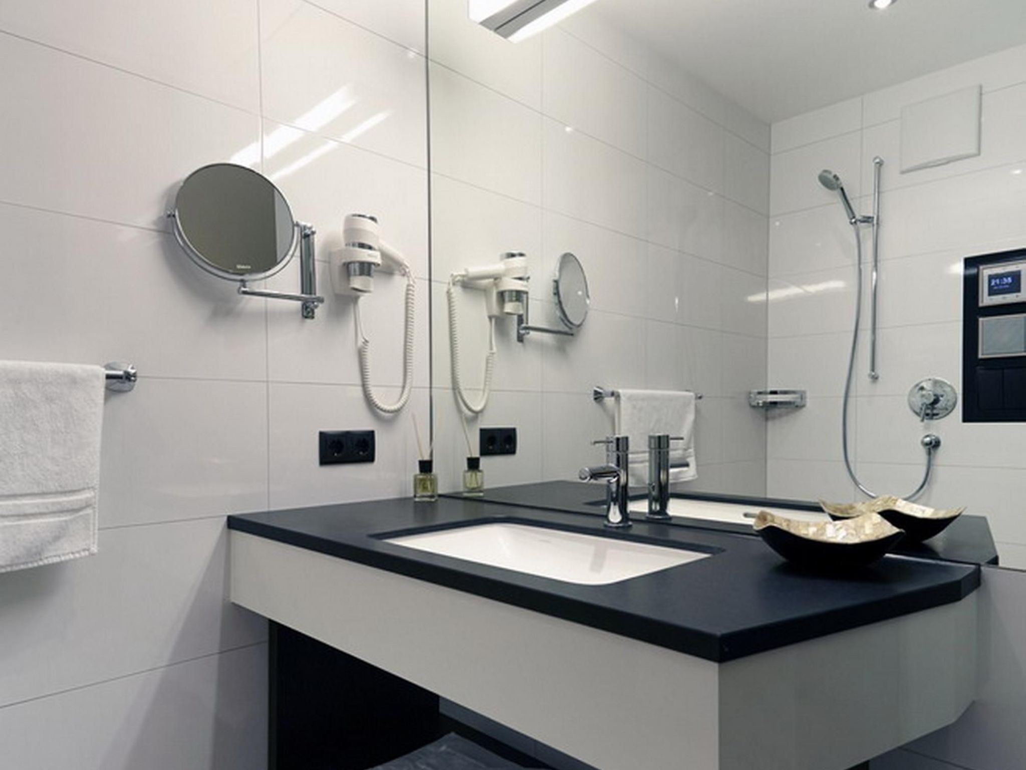 Une salle de bain moderne avec deux lavabos, un miroir, un porte-serviettes et une douche.