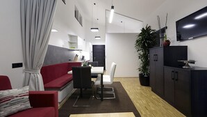 Et moderne, kompakt opholdsrum med en rød sofa, et spisebord og et tekøkken.