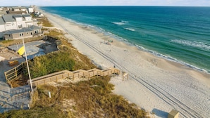 A beachside property with a sandy beach, a wooden walkway leading to the shore, and a view of the ocean.