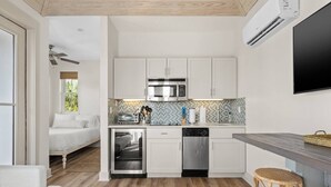 A compact kitchen with white cabinets, a microwave, a toaster, and a dishwasher.