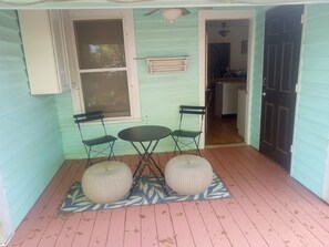 A porch with a table and chairs, a small window, and a door leading to a kitchen.