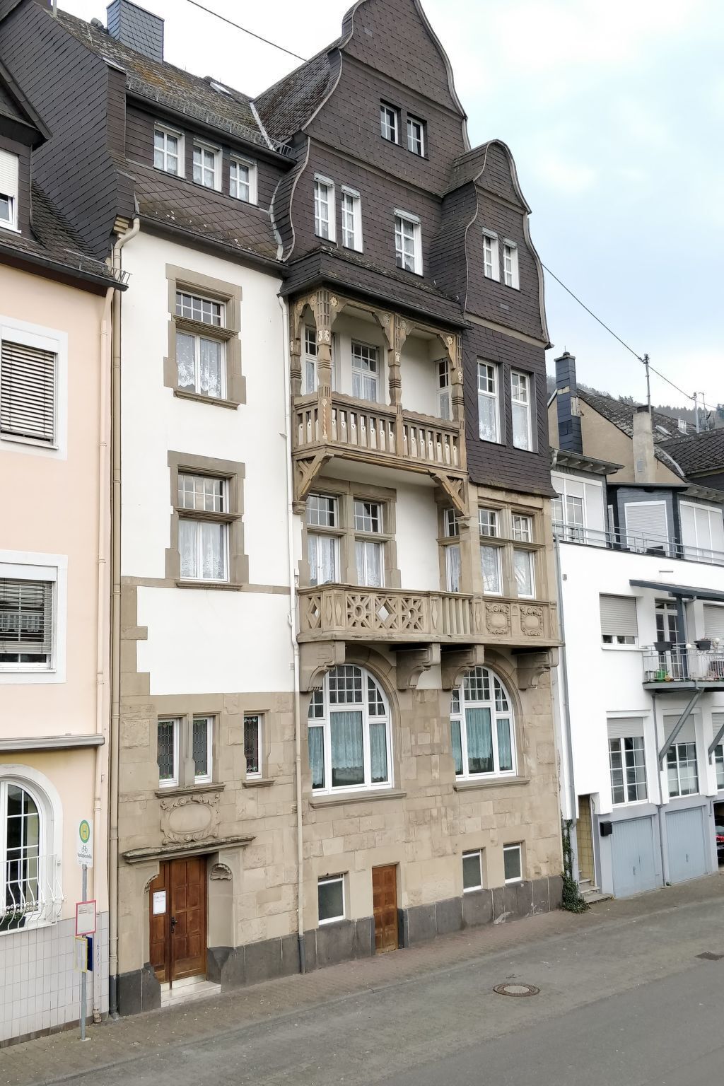 A multi-story building with a balcony on the second floor, a wooden door, and a small window on the ground floor.