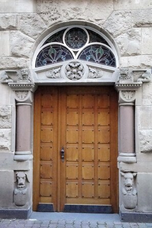 Una gran puerta de madera con un arco decorativo encima, flanqueada por esculturas de leones de piedra.
