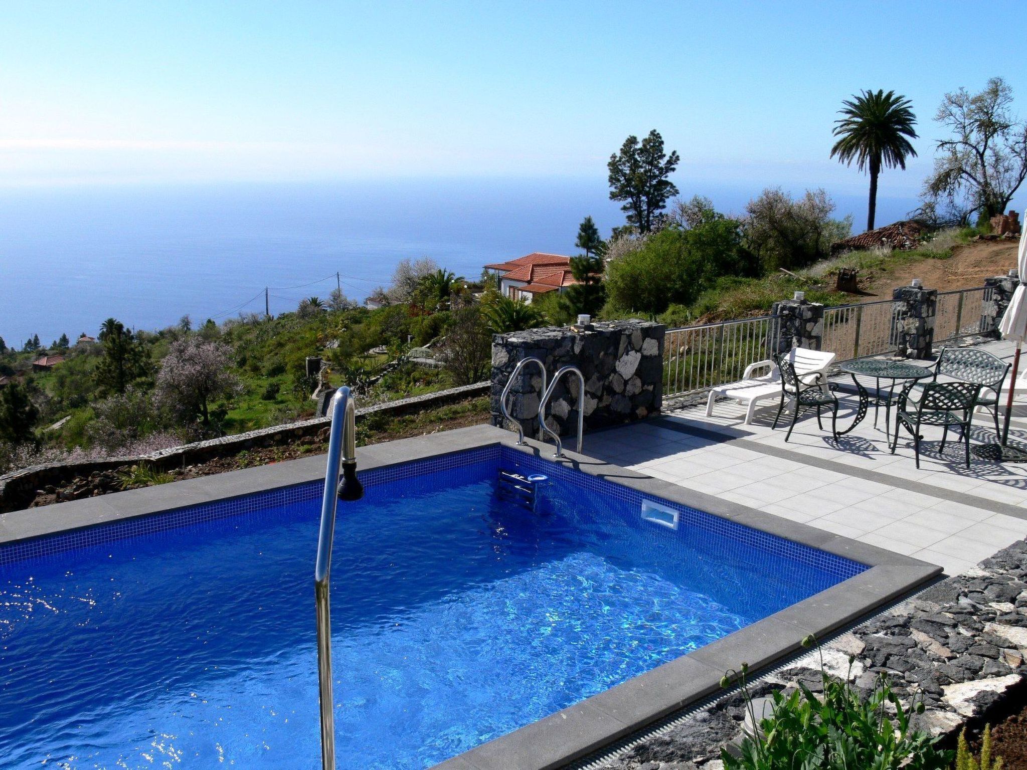 A swimming pool with a stone wall and a view of the sea.