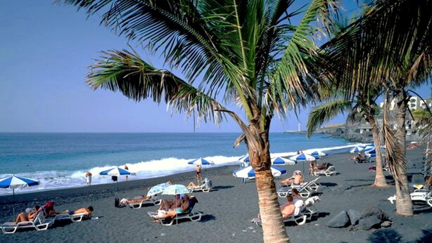 A beach with palm trees, umbrellas, and people sunbathing. - Nettes Ferienhaus in Tijarafe mit Privatem Pool und Panoramablick by Interhome (Tijarafe)