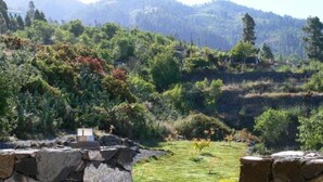 A stone pathway leading through a lush garden with a view of distant hills. - Nettes Ferienhaus in Tijarafe mit Privatem Pool und Panoramablick by Interhome (Tijarafe)