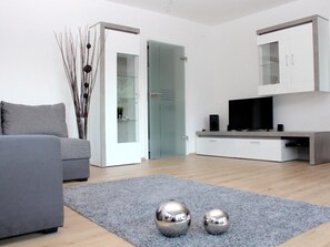 A modern living room with a grey sofa, a flat-screen TV, and a minimalist cabinet. - Apartment Larum by Interhome (Bringhausen)