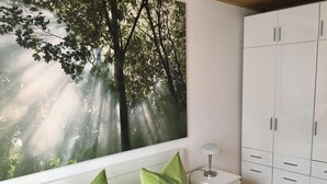 Una habitación con un ventanal grande, un armario blanco y una almohada verde.