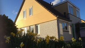 Une maison à deux étages avec une façade en briques et un revêtement extérieur jaune.