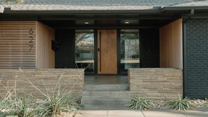 A modern building with a wooden door, stone steps, and a brick facade. - NEW Boutique Historical Home Downtown Edmond (Edmond)