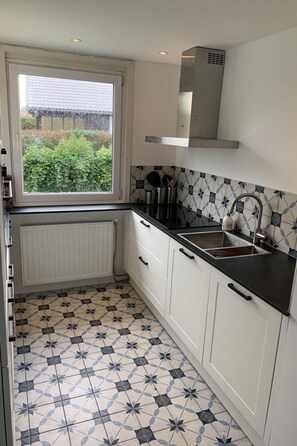 Een koelkast, een oven, een vaatwasser, kookgerei, borden en bestek