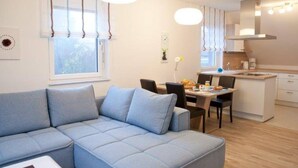 Een moderne woonkamer met een modulaire bank, een eethoek en een keuken.