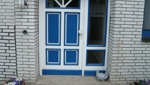 Eine weiße Tür mit blauen Verzierungen und einem kleinen Fenster.