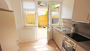 A compact kitchen with a built-in oven, a sink, and a window overlooking a wooden deck.